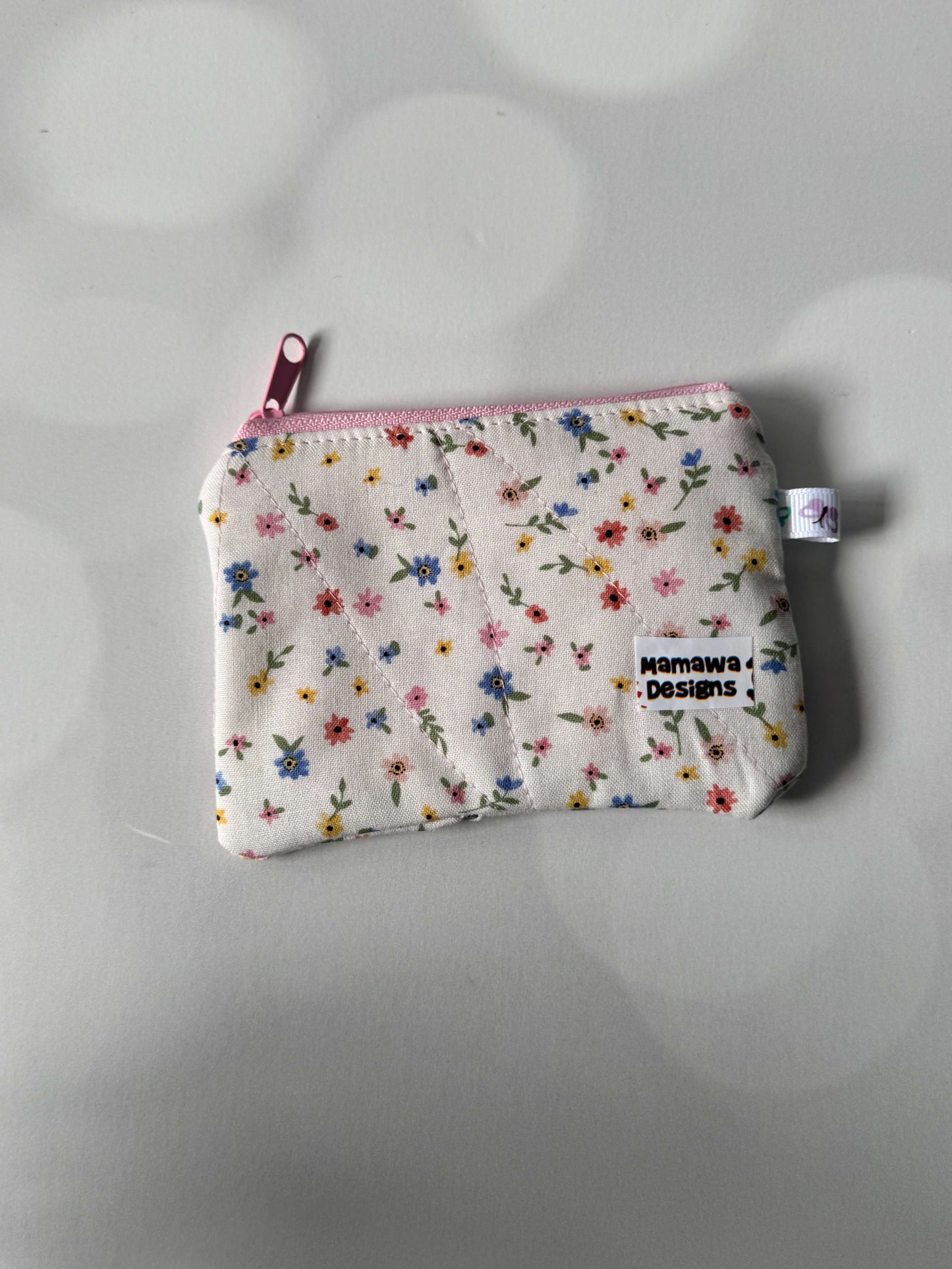 White floral coin wallet with a zip closure, perfect for storing coins and small essentials.