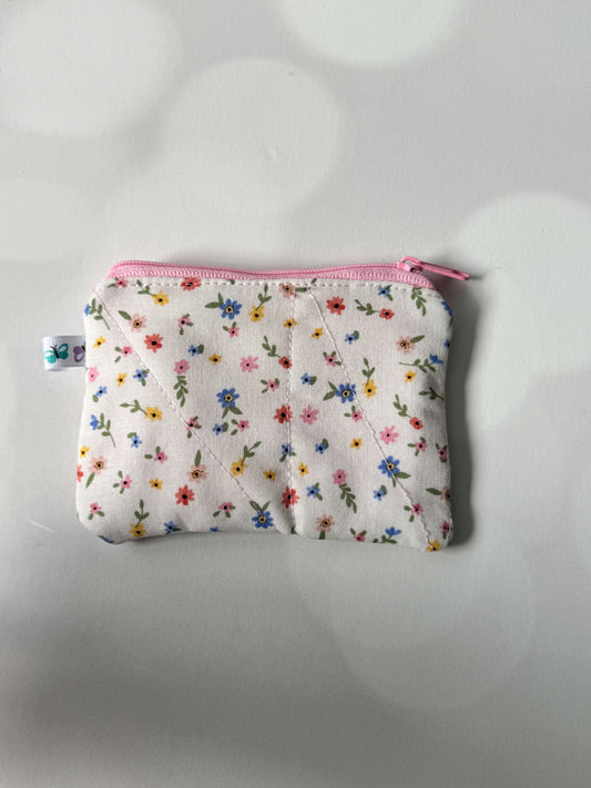 White floral coin wallet with a pink zipper, perfect for storing coins and small essentials.
